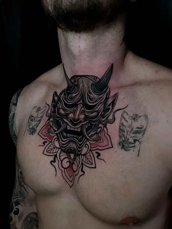 Illustrative demon mask tattoo on chest.