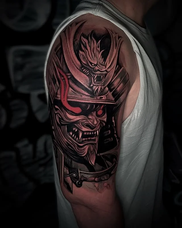 Large illustrative tattoo of a samurai mask on arm.