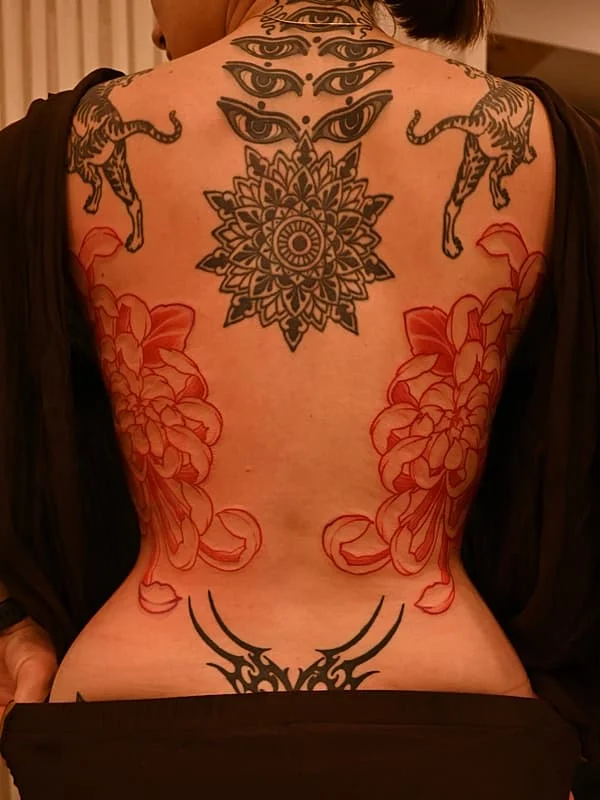 Large illustrative back tattoo with floral and geometric designs.