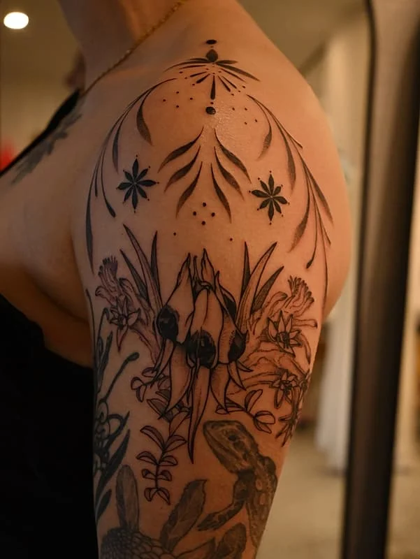 Blackwork floral tattoo on shoulder and arm.