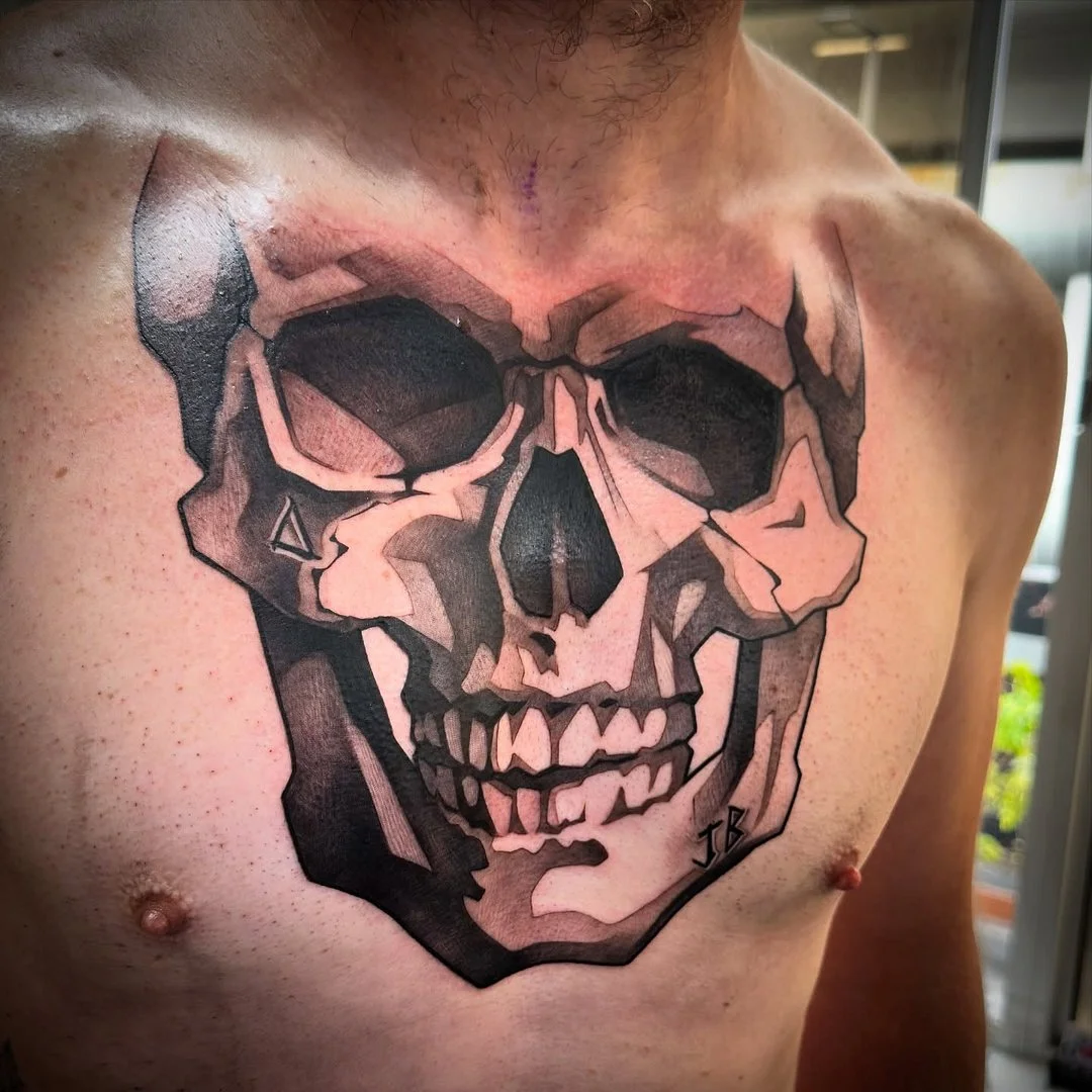Realistic black-and-grey skull tattoo on chest.