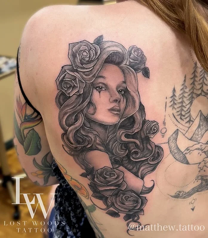Black and grey tattoo of a woman with roses on back.