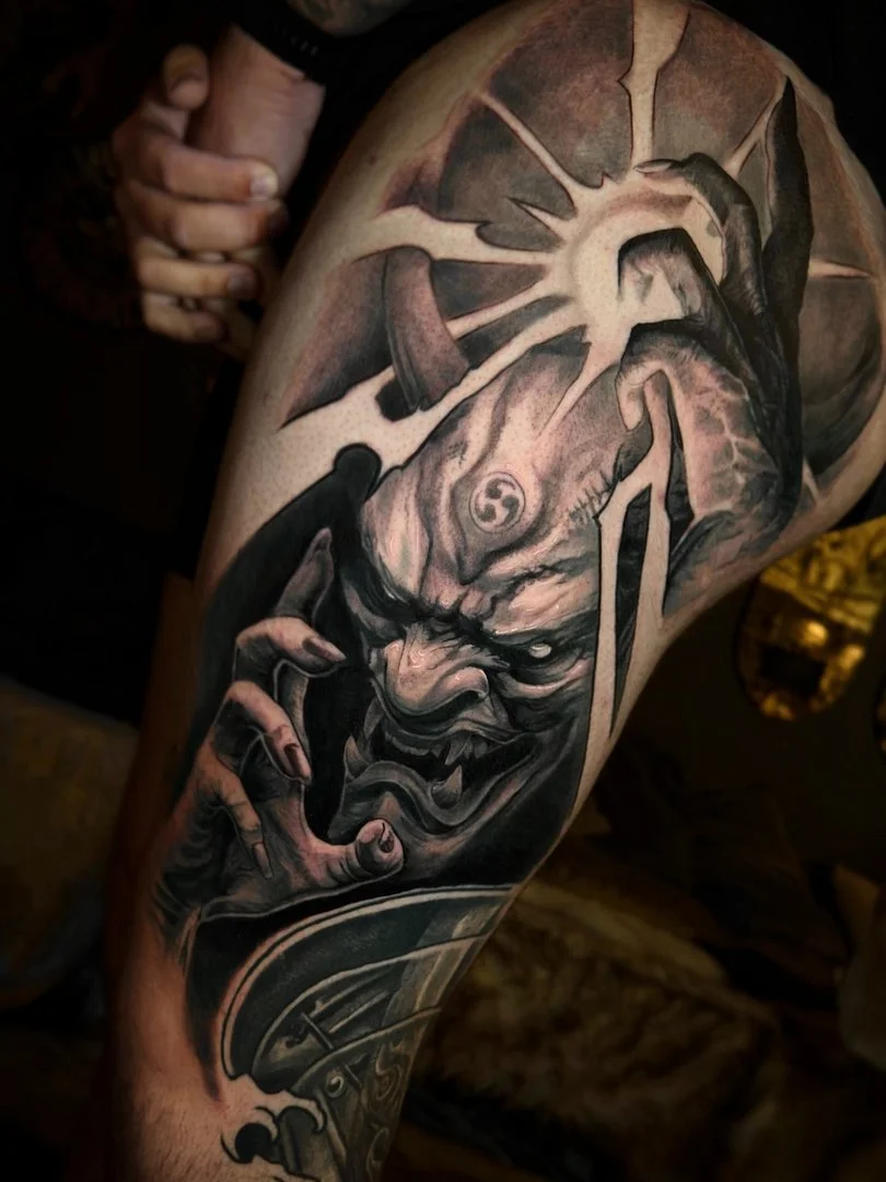 Large black-and-grey demon tattoo on thigh.