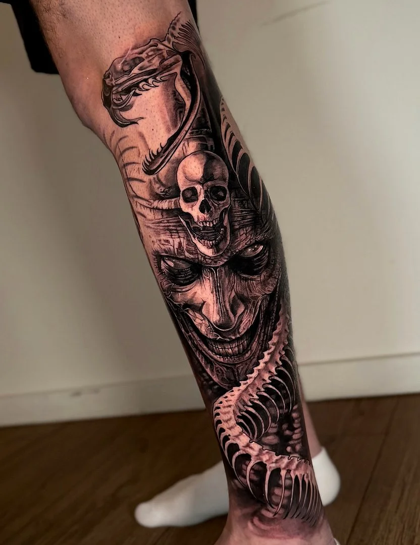 Detailed black and grey tattoo on calf featuring skull and snake.