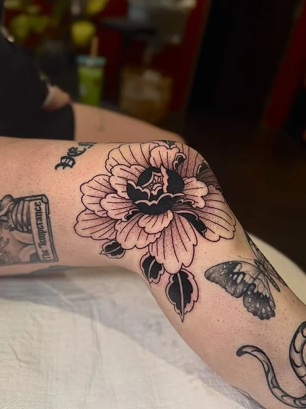 Black and grey peony tattoo on the arm.