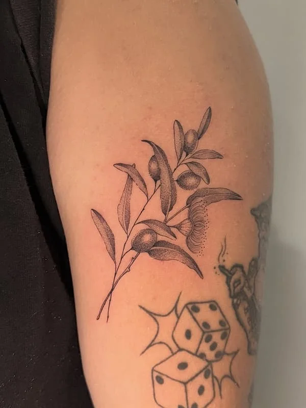Black-and-grey olive branch tattoo on upper arm.