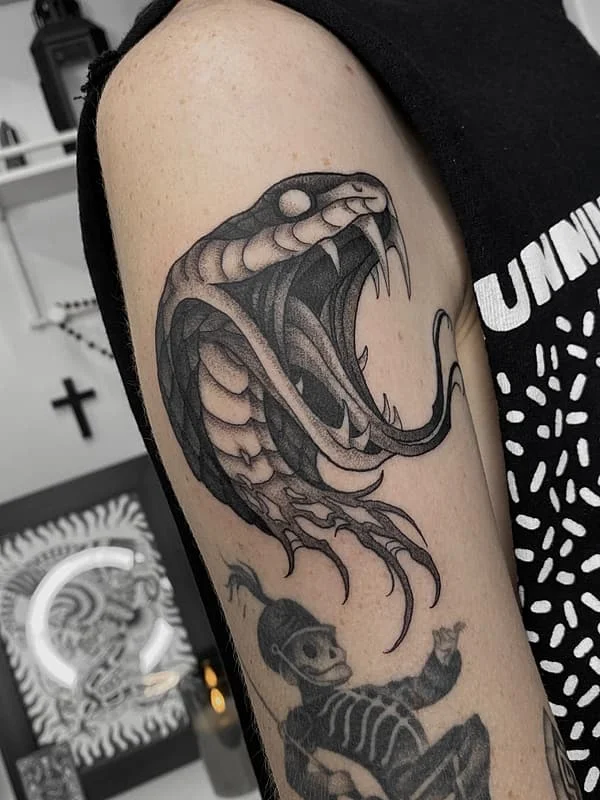 Black-and-grey snake tattoo on arm.