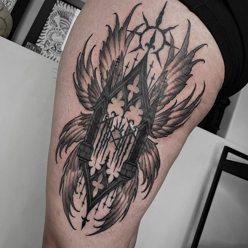 Large black-and-grey winged gothic tattoo on thigh.