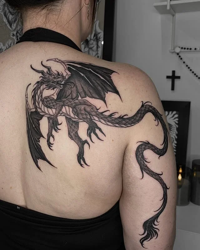 Large black and grey dragon tattoo on back and shoulder.