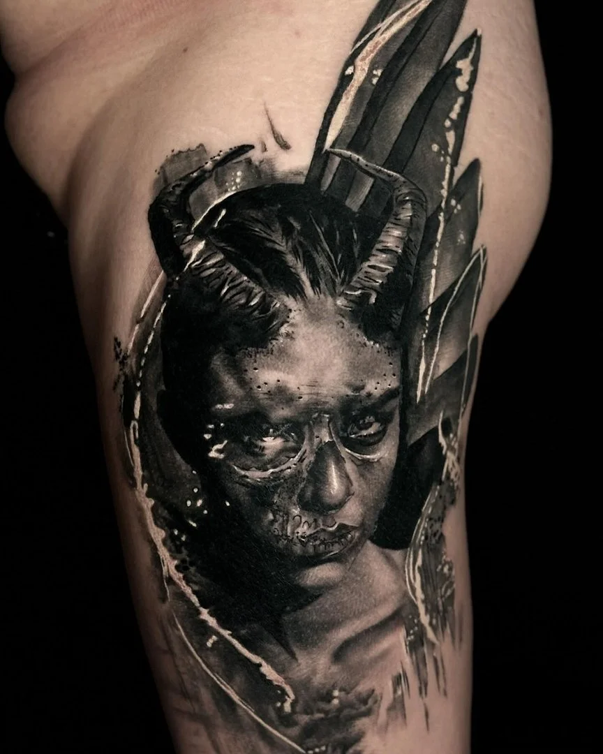 Large black-and-grey portrait tattoo on arm.
