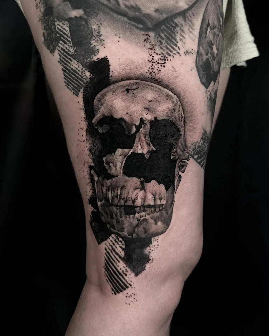 Realistic black-and-grey skull tattoo on thigh.