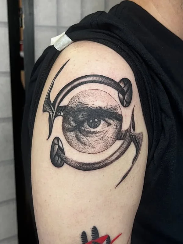 Black and grey eye tattoo on upper arm.