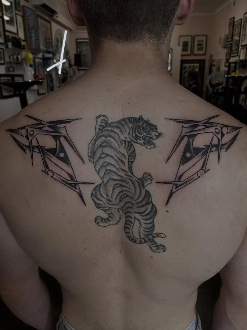 Large black-and-grey tiger tattoo on a man's back.