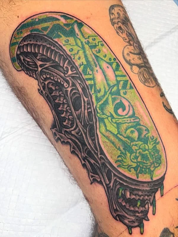 Detailed skull tattoo with green elements on leg.