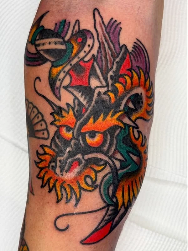 Vibrant dragon tattoo on forearm with bold colors.