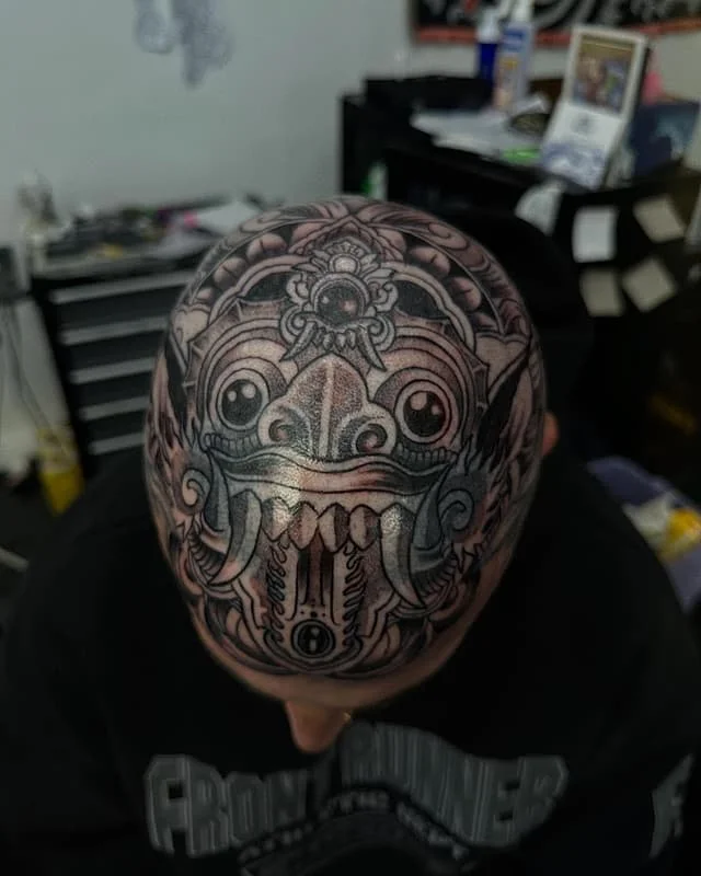 Large blackwork tattoo of a mythical creature on the scalp.