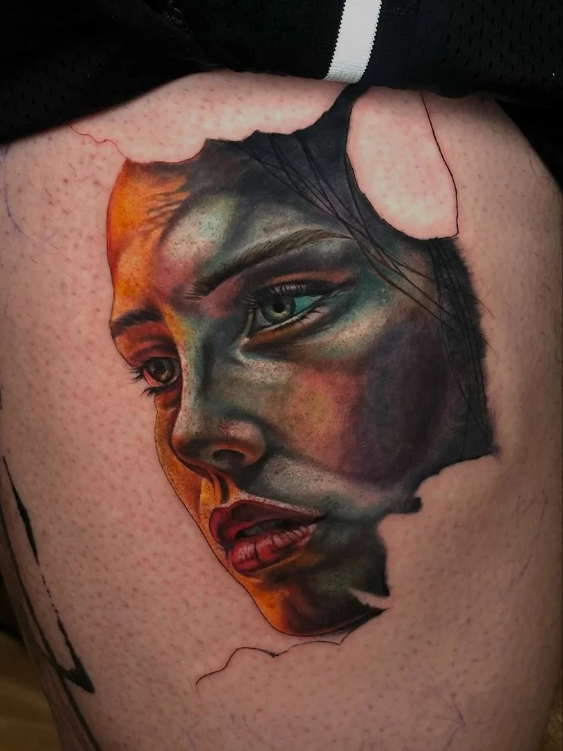 Realistic portrait tattoo on thigh depicting a woman's face.