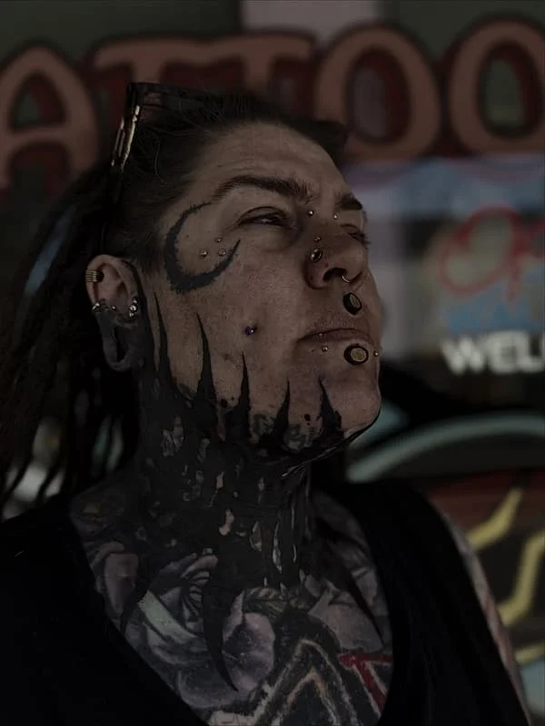 Intricate blackwork tattoo on face and neck.