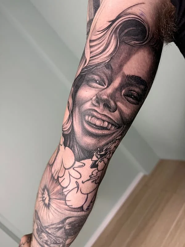 Realistic black-and-grey portrait tattoo on forearm.