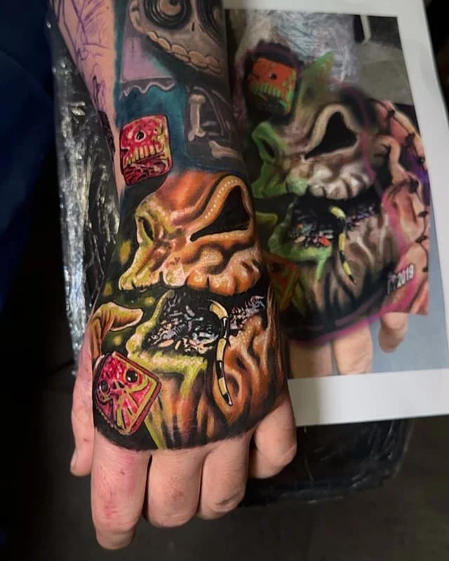Vibrant illustrative tattoo on a hand featuring creepy-crawly elements.