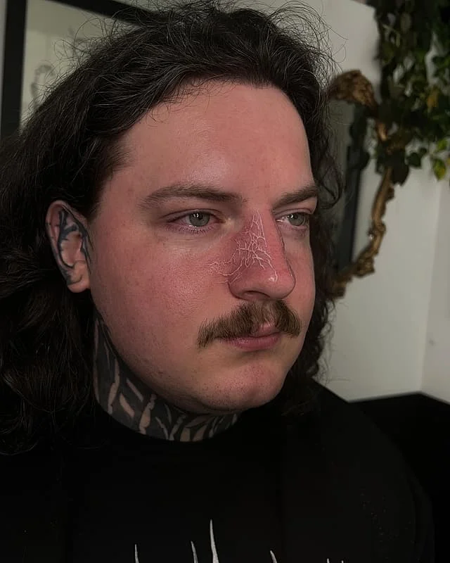 Abstract blackwork tattoo on face and neck.