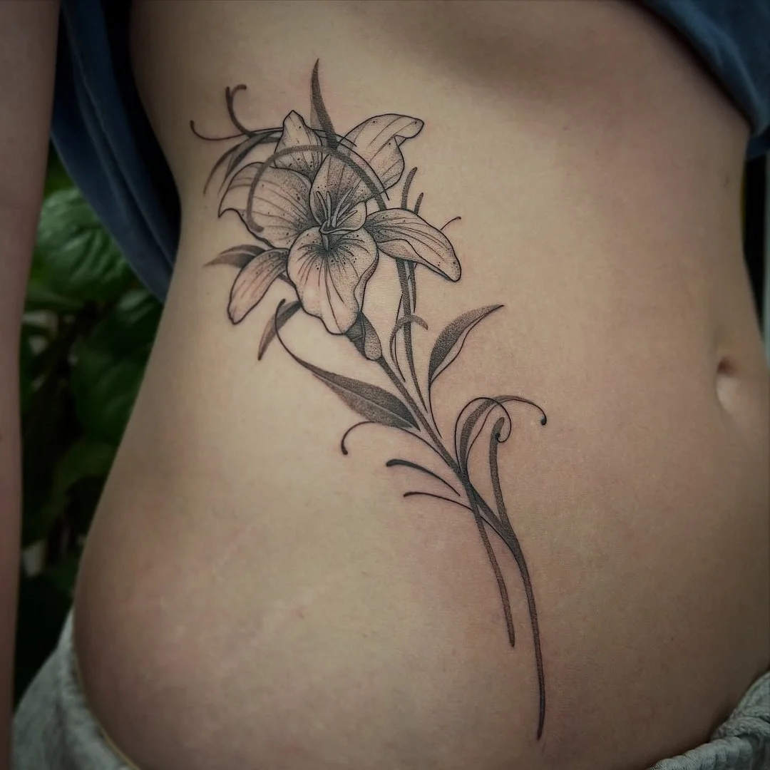 Black-and-grey flower tattoo on rib area.