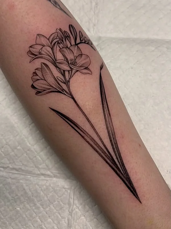 Fine-line flower tattoo on a forearm.