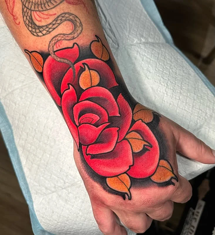 Traditional rose tattoo on a hand with vibrant colors.