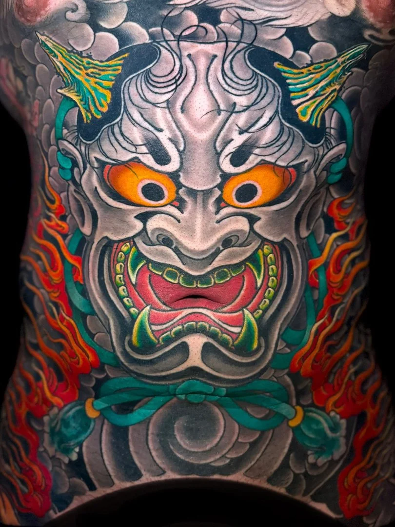 Vibrant Japanese tattoo of a demon face on chest.