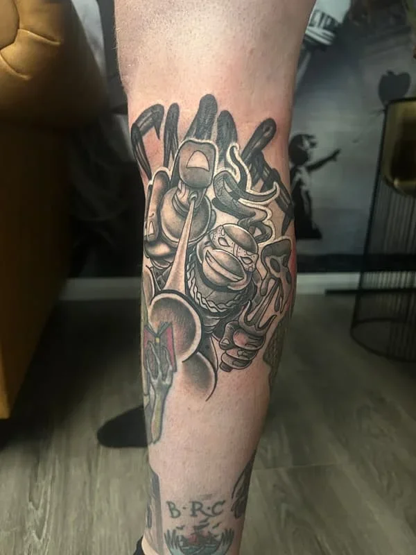 Large illustrative black and grey calf tattoo with abstract figures