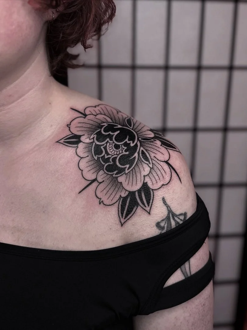 Black and grey floral tattoo on shoulder and arm