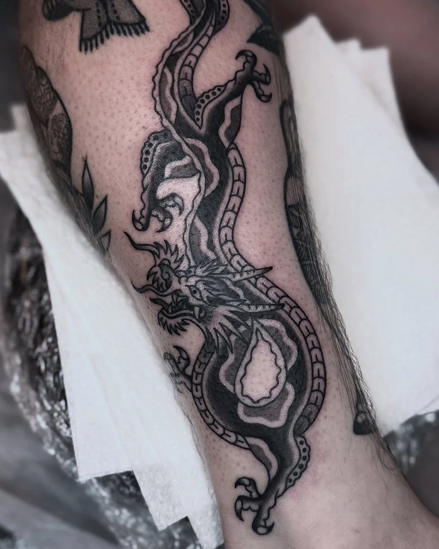 Detailed blackwork dragon tattoo on forearm demonstrating compact Chinese-style composition