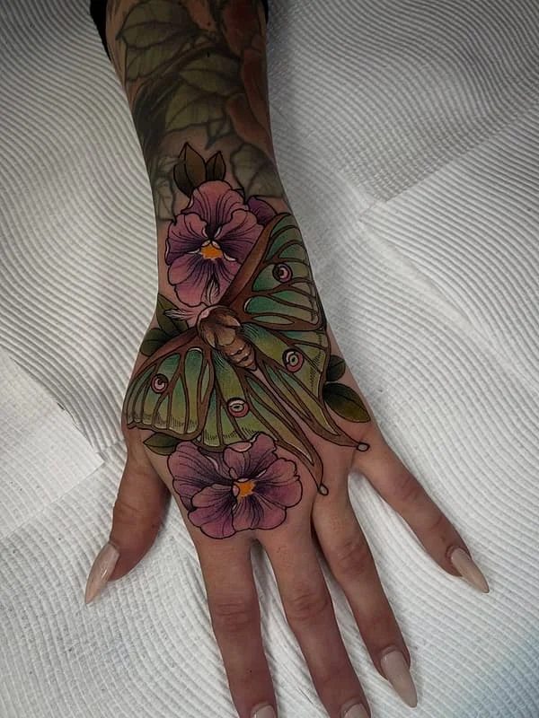Colorful butterfly and flower tattoo on a hand.
