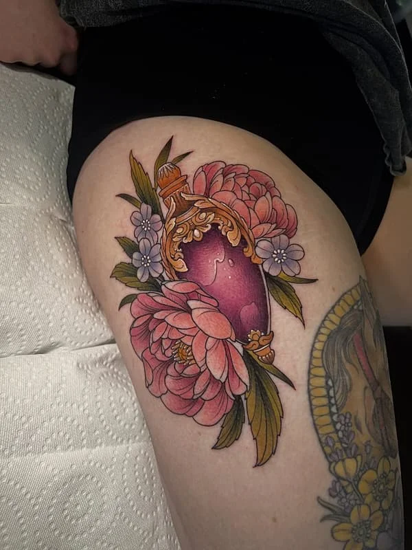 Colorful floral tattoo of a vase on thigh.