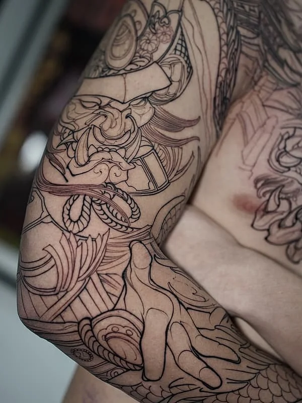 Large blackwork tattoo on arm featuring intricate designs.
