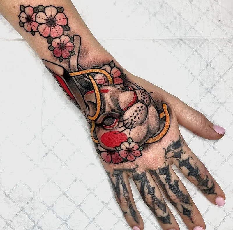 Colorful rabbit tattoo with flowers on a hand.