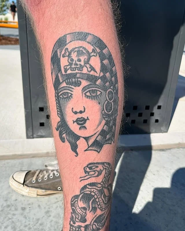 Traditional blackwork tattoo of a woman and snake on leg.
