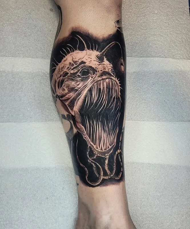 Detailed black-and-grey ocean monster tattoo on calf.