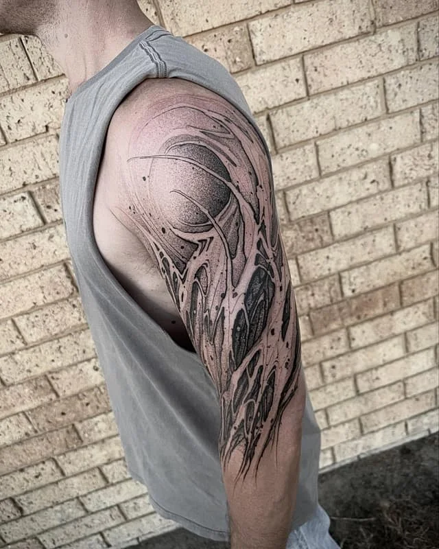 Large biomechanical blackwork tattoo on a man's arm.