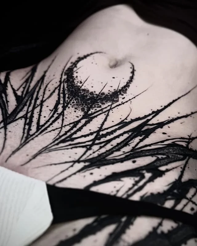 Abstract blackwork tattoo on chest and rib area.