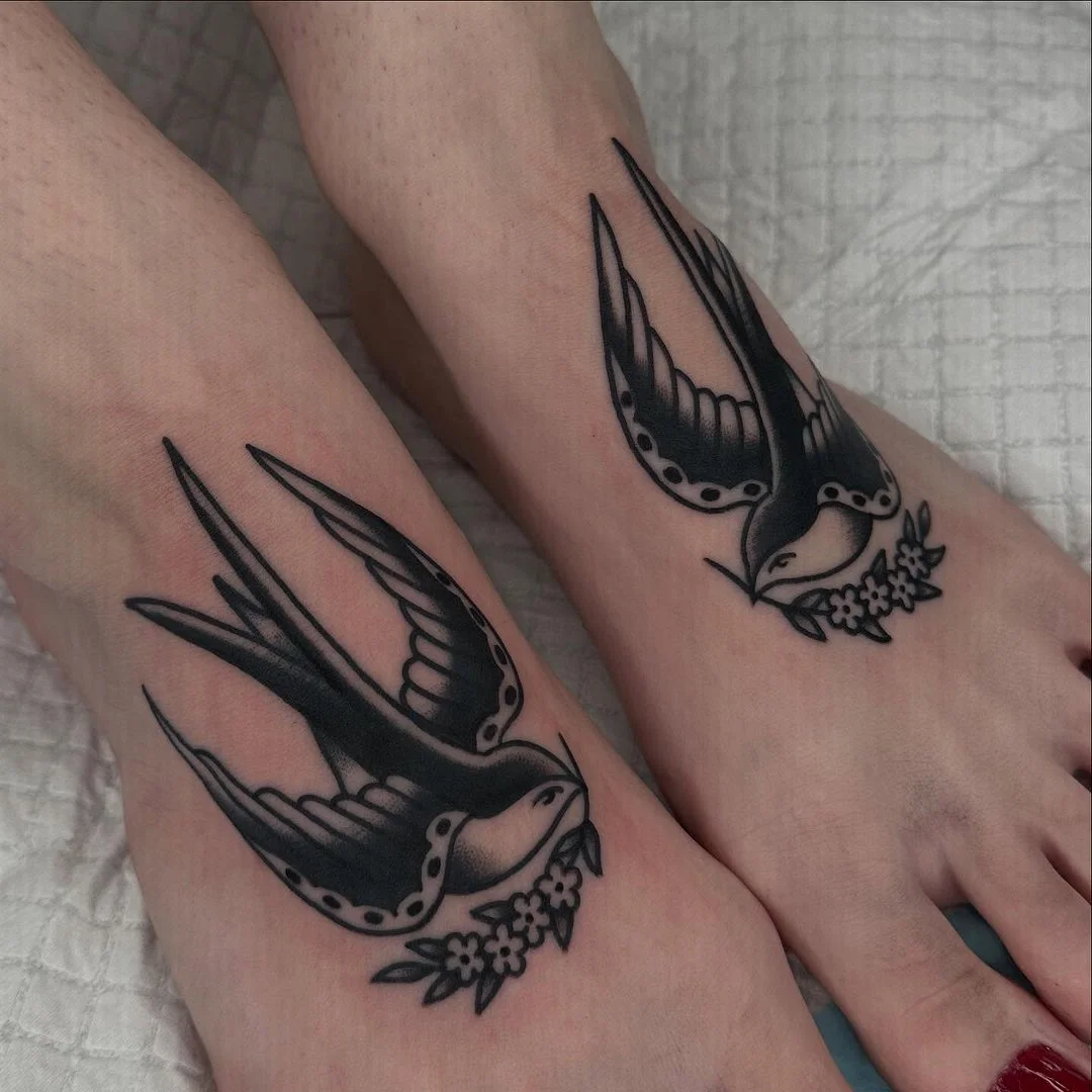 Traditional blackwork swallow tattoos on ankles.