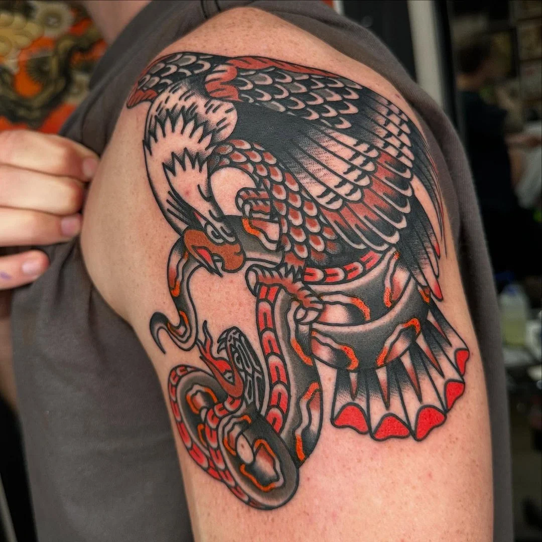 Traditional tattoo of an eagle and snake on shoulder.