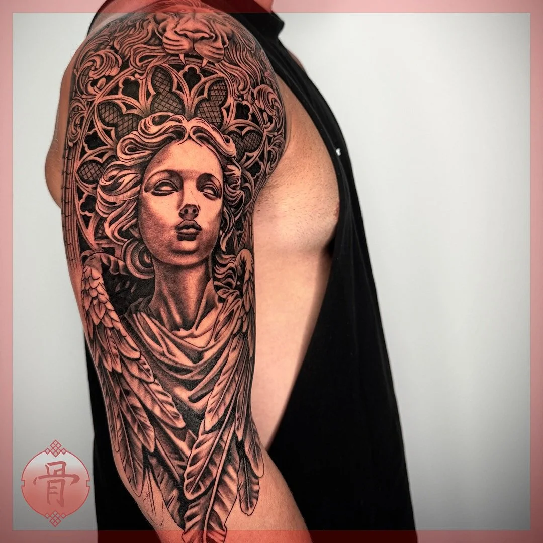 Detailed black-and-grey angel tattoo on arm.
