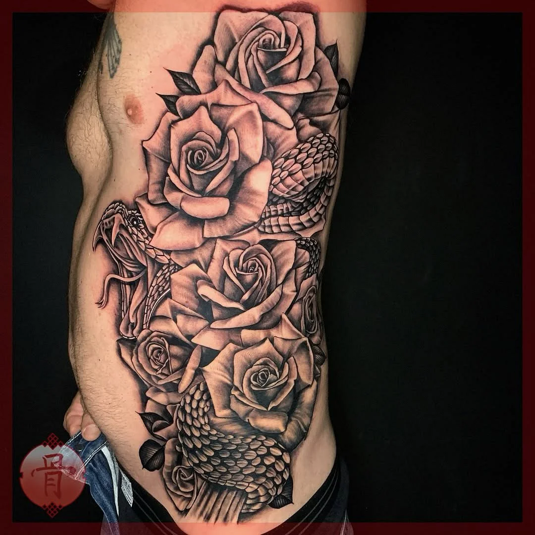 Large black-and-grey tattoo of roses and a snake on rib.
