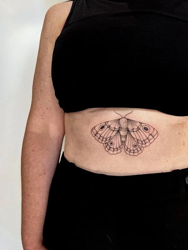 Fine-line butterfly tattoo on a woman's rib.