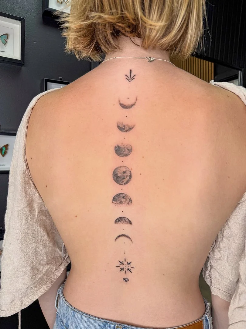 Black and grey moon phases tattoo on a woman's back.