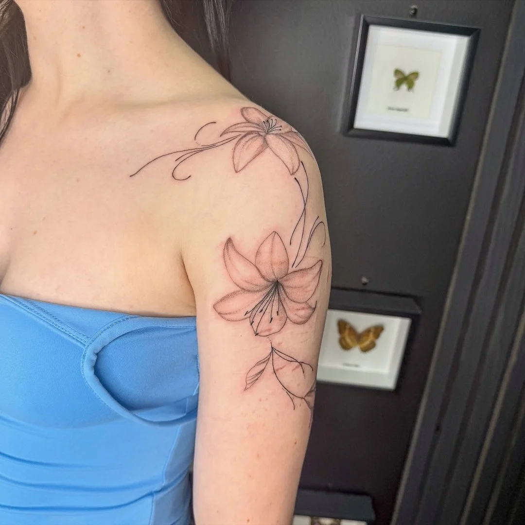 Delicate fine-line floral tattoo on shoulder and arm.