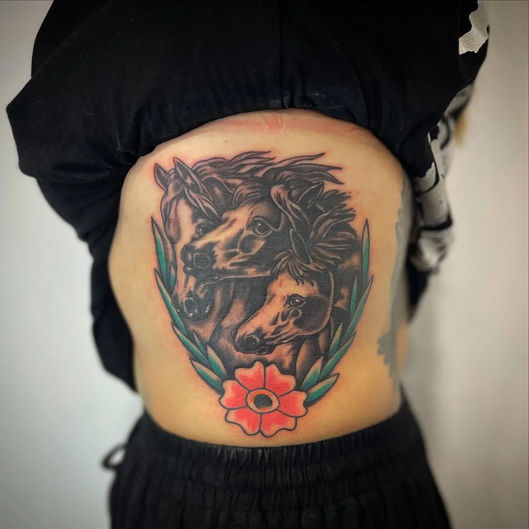Tattoo of three horses and a flower on rib.