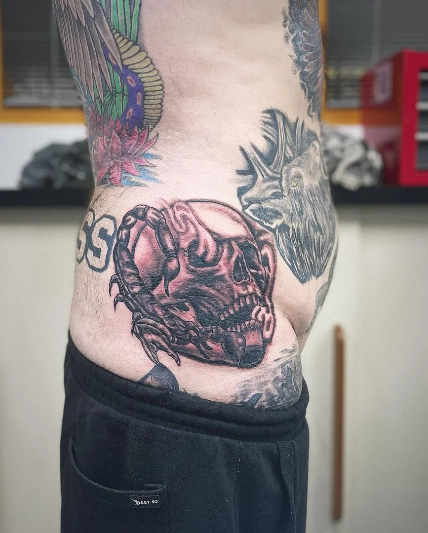 Black-and-grey skull and crab tattoo on rib.