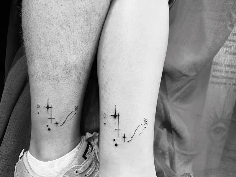 Minimalist blackwork tattoo of stars on ankle.